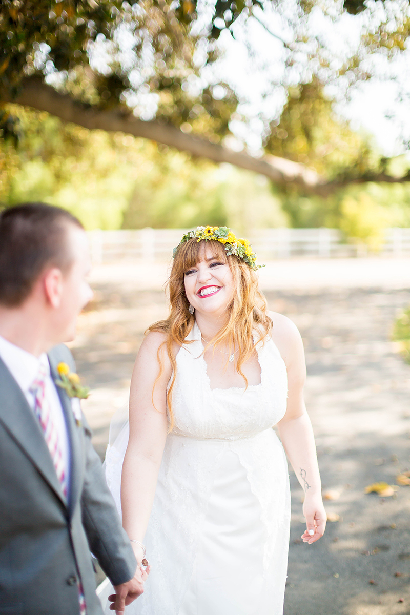 A bride and groom walk together wearing a flower crown and a white dress and a gray suit for this Camarillo Ranch wedding photography session