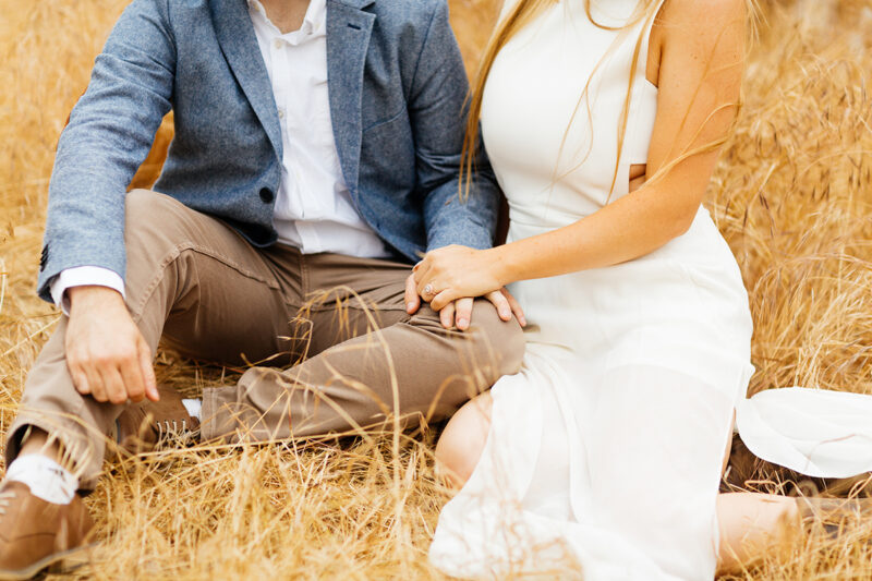 An engaged couple sit holding each other in a field for this Granada Hills engagement photography session