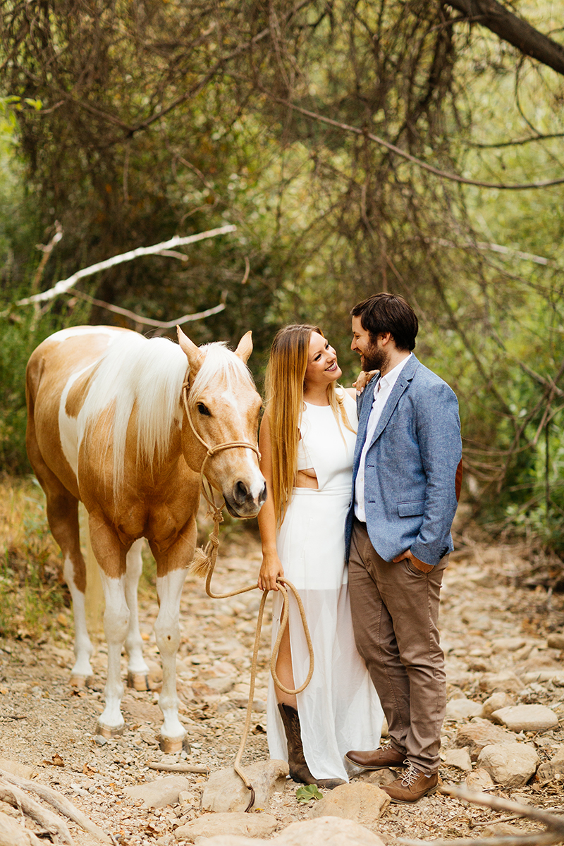 An engaged couple hold each other with their horse on a trail for this Granada Hills engagement photography session