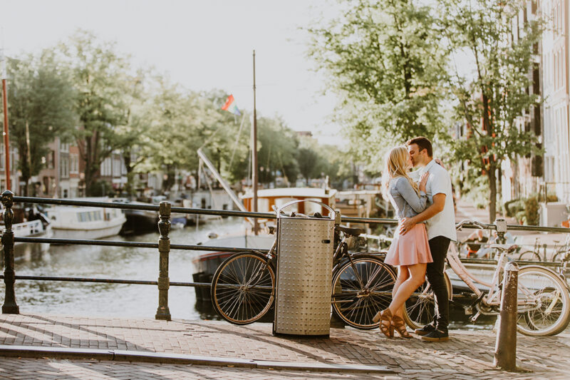 A couple hold one another close and kiss on a bridge over a canal for this Amsterdam couples photography session