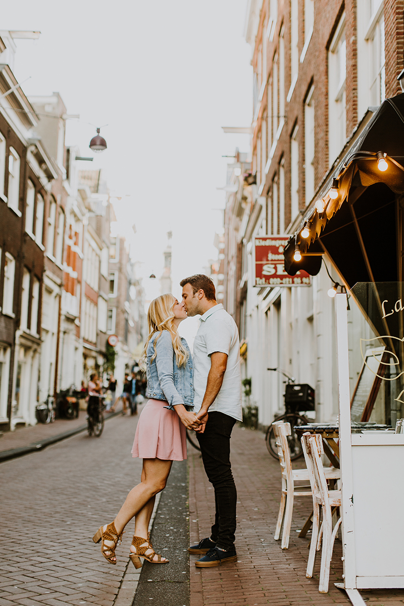 A couple hold one another close and kiss in a cute neighborhood for this Amsterdam couples photography session