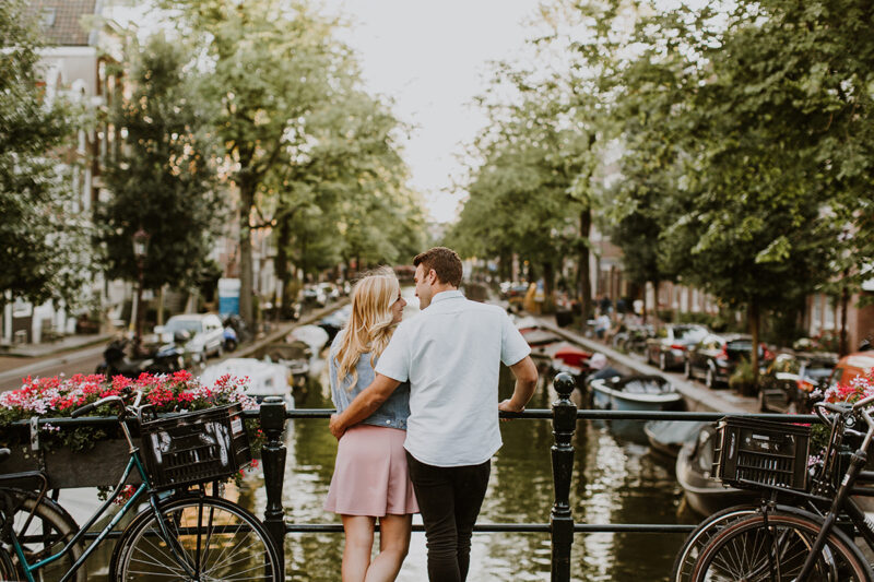 A couple hold one another close on a bridge over a canal for this Amsterdam couples photography session