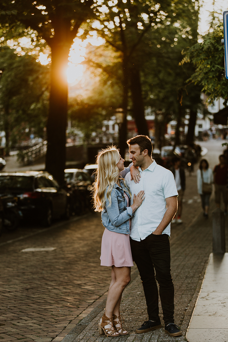 A couple hold one another close next to a canal at sunset for this Amsterdam couples photography session