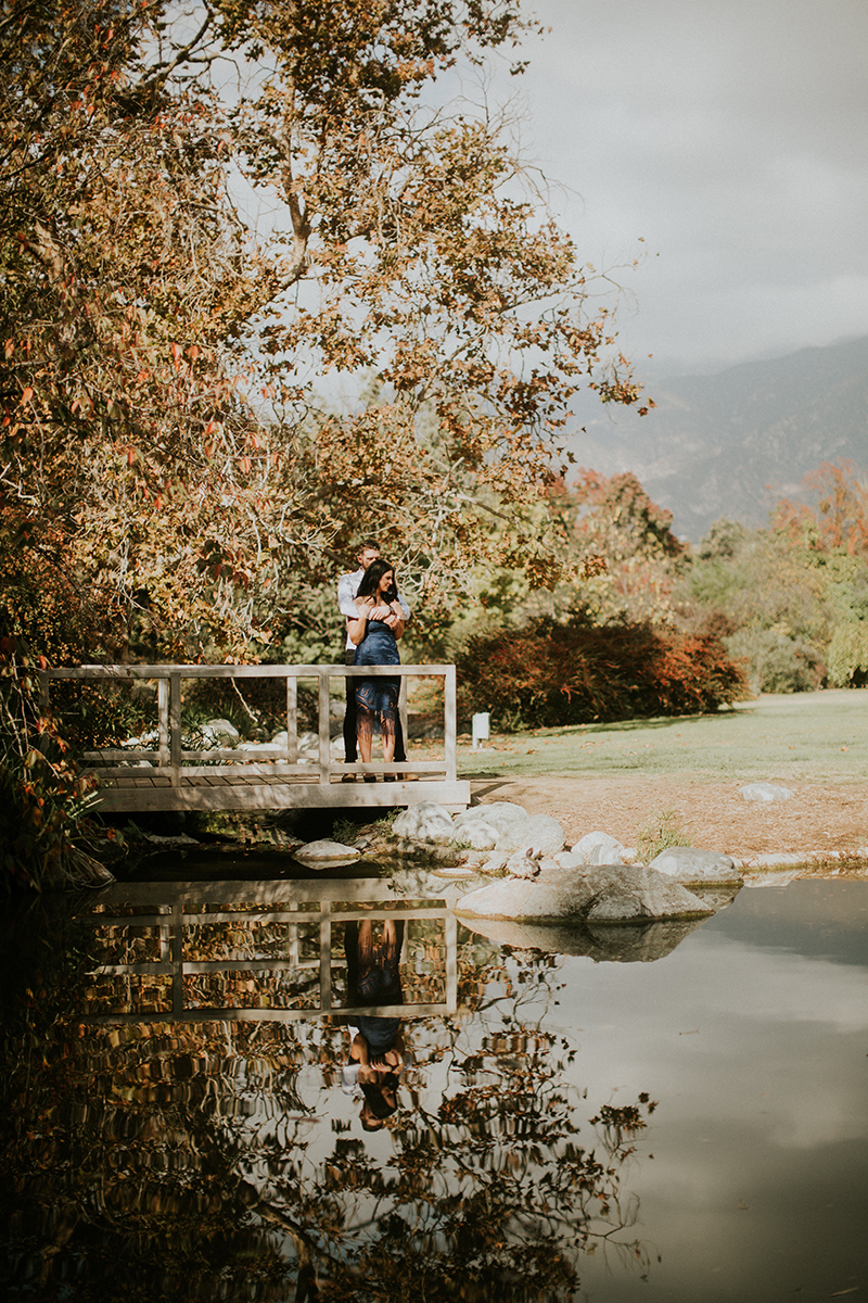A couple hold each other on a bridge at the Los Angeles County Arboretum and Botanic Garden for this Los Angeles engagement photography session