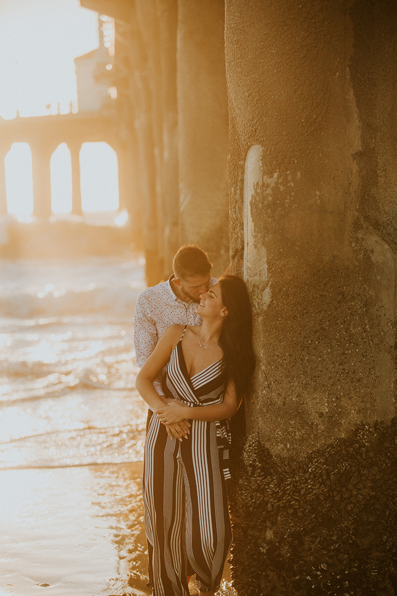 A couple hold one another at sunset on the beach near the Santa Monica Pier for this Los Angeles engagement photography session