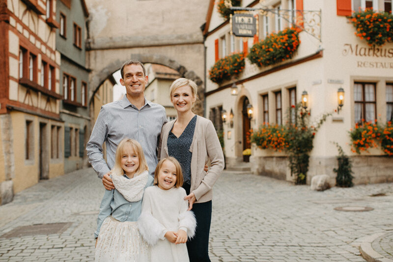A family poses together smiling in Germany wearing coordinated outfits for a Rothenburg ob der Tauber family photography session