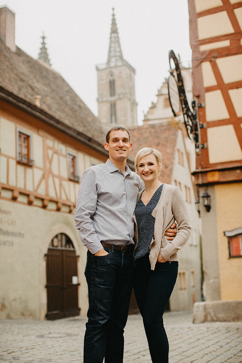 A couple hold one another in Germany wearing coordinated outfits for a Rothenburg ob der Tauber family photography session