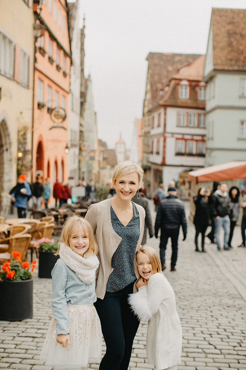 A mother walks with her daughters in Germany wearing coordinated outfits for a Rothenburg ob der Tauber family photography session