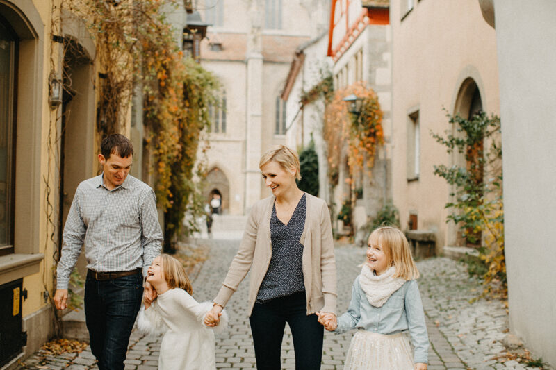 A family walks together holding hands in Germany wearing coordinated outfits for a Rothenburg ob der Tauber family photography session