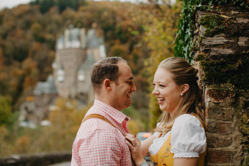 A couple embrace on the road to Burg Eltz wearing a traditional dirndl and lederhosen for these Eltz Castle couples photos in Germany