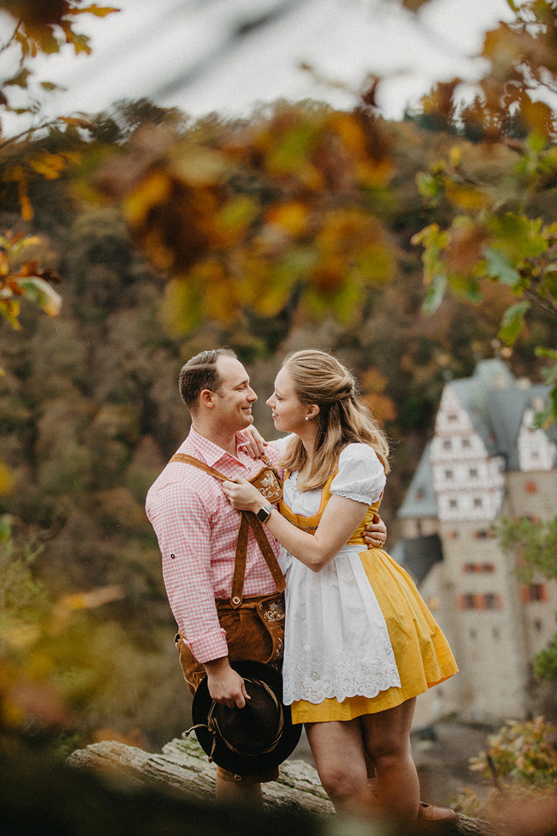 A couple embrace near Burg Eltz wearing a traditional dirndl and lederhosen for these Eltz Castle couples photos in Germany