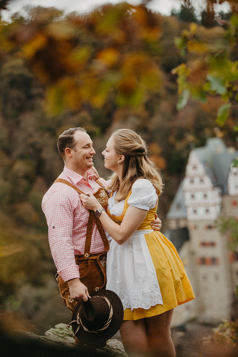 A couple embrace near Burg Eltz wearing a traditional dirndl and lederhosen for these Eltz Castle couples photos in Germany