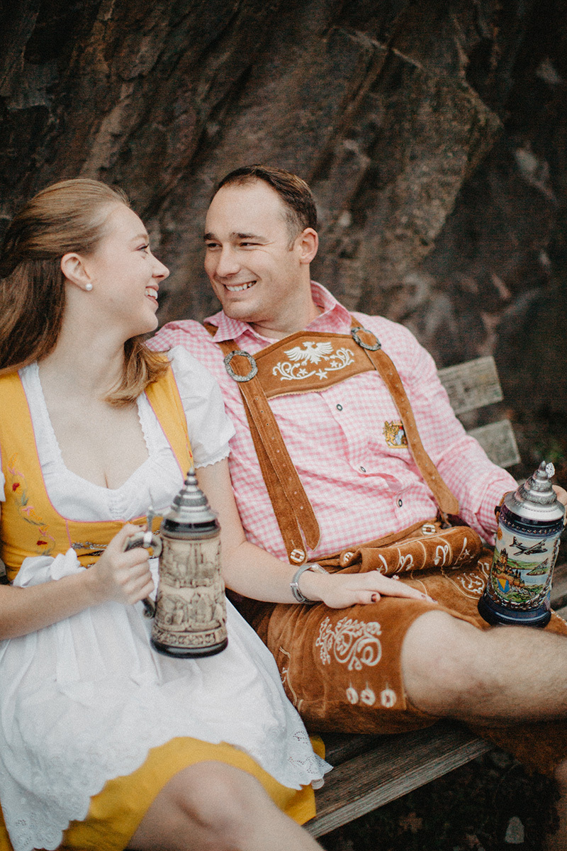 A couple embraces holding steins near Burg Eltz wearing a traditional dirndl and lederhosen for these Eltz Castle couples photos in Germany