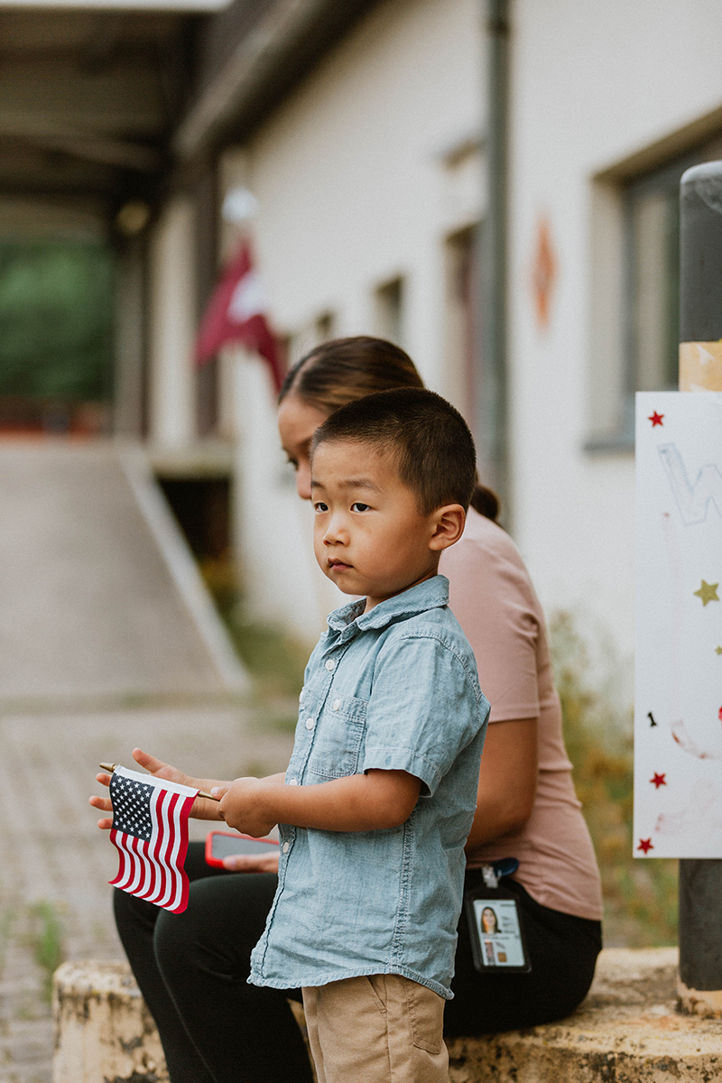 A young boy waiting with an American flag at the Rhineland Ordnance Barracks for Kaiserslautern homecoming photos in Germany