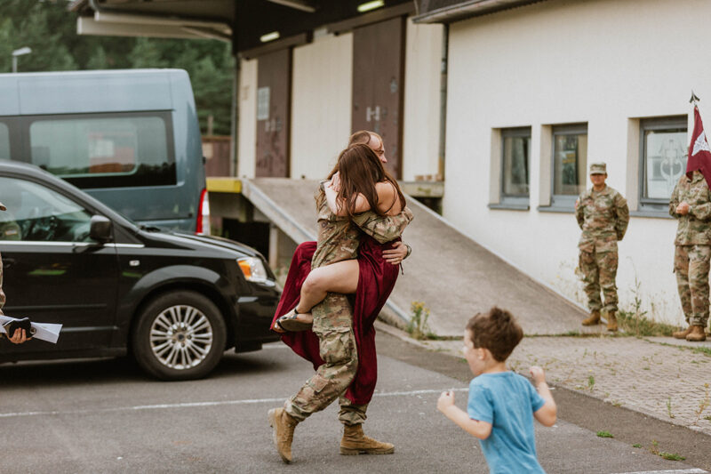 A woman jumps into her husbands arms at the Rhineland Ordnance Barracks for Kaiserslautern homecoming photos in Germany