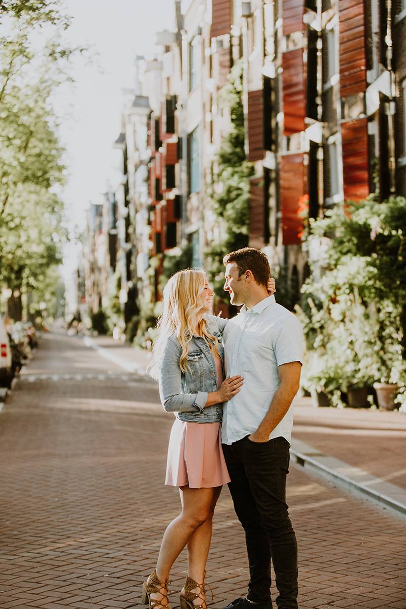 A couple hold one another close in a cute neighborhood next to a canal for this Amsterdam couples photography session