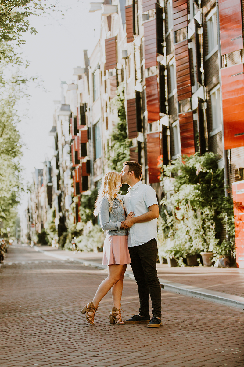 A couple hold one another close in a cute neighborhood next to a canal for this Amsterdam couples photography session