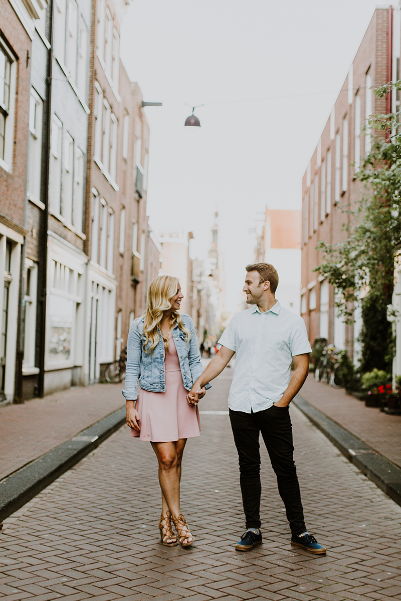 A couple hold each other's hands and walk in a cute neighborhood for this Amsterdam couples photography session