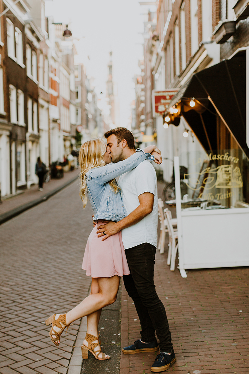 A couple hold one another close and kiss in a cute neighborhood for this Amsterdam couples photography session