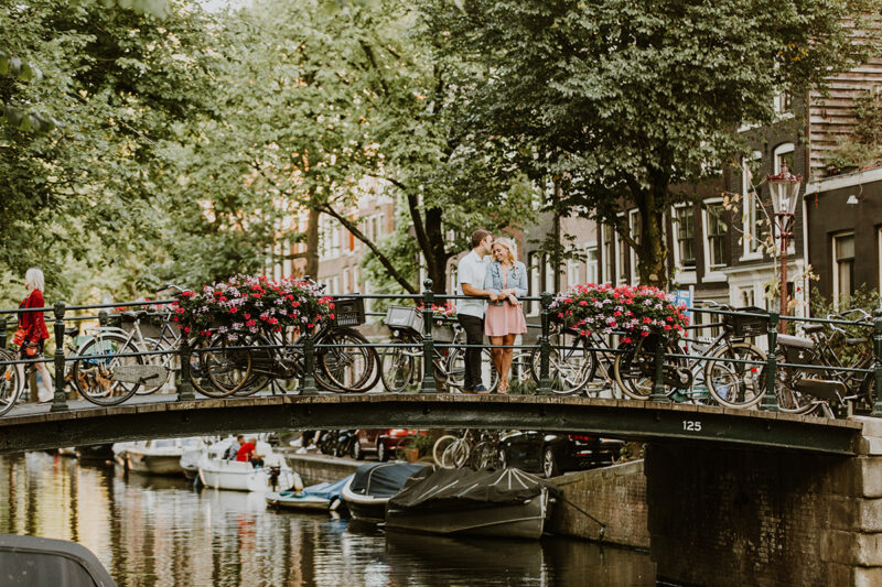 A couple hold one another close on a bridge over a canal for this Amsterdam couples photography session