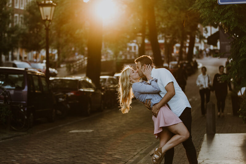 A couple hold one another close and kiss next to a canal at sunset for this Amsterdam couples photography session