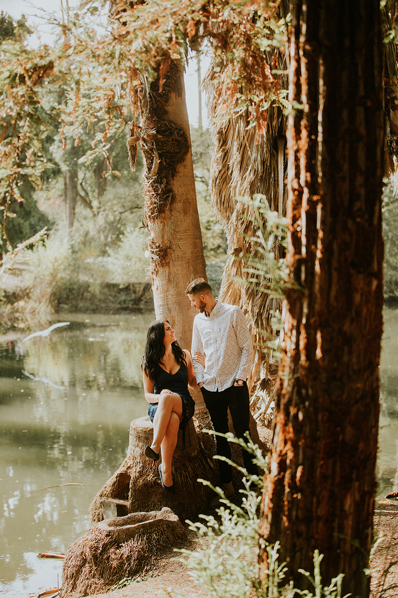 A couple hold each other in a forest near water at the Los Angeles County Arboretum and Botanic Garden for this Los Angeles engagement photography session