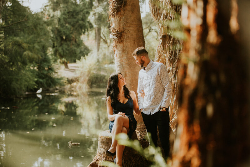 A couple hold each other in a forest near water at the Los Angeles County Arboretum and Botanic Garden for this Los Angeles engagement photography session