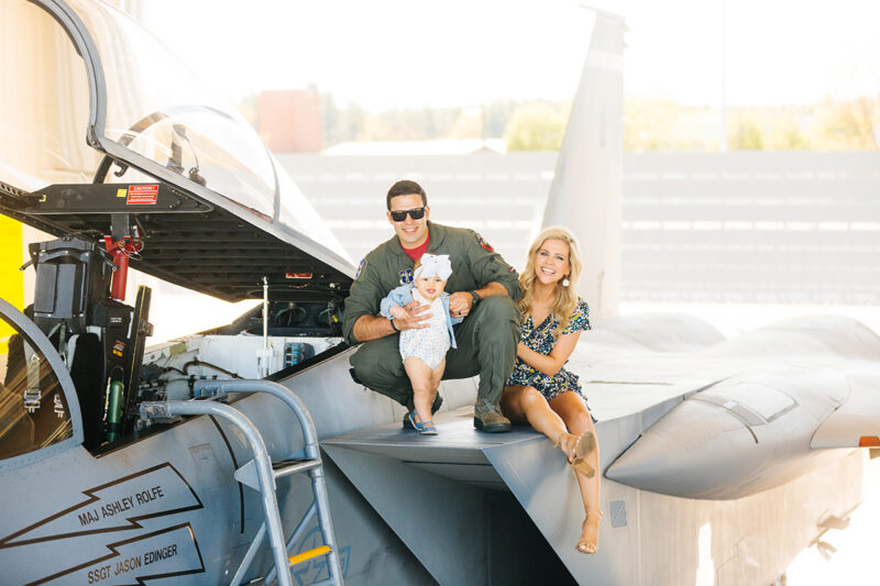 A family sits on the wing of an F-15 at Barnes Air National Guard Base wearing a flight suit and a coordinated outfit for these F-15 fighter pilot family photos