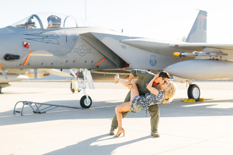 A pilot dips his wife and kisses her in front of an F-15 at Barnes Air National Guard Base wearing a flight suit and a coordinated outfit for these F-15 fighter pilot family photos
