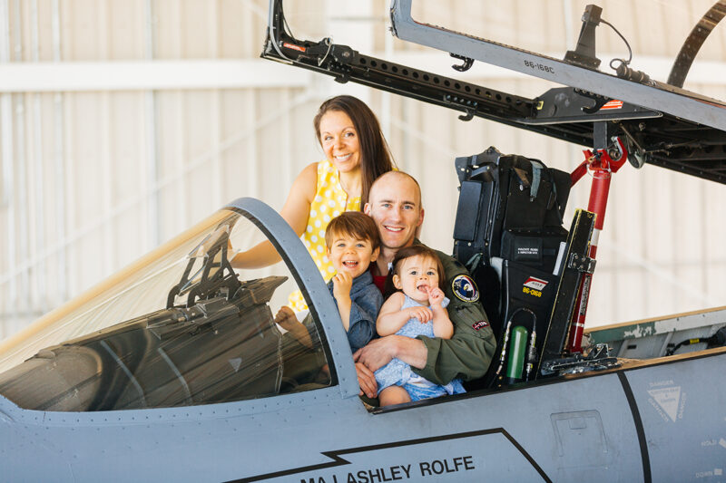 A family sits in the cockpit of an F-15 at Barnes Air National Guard Base near Boston wearing a flight suit and coordinated outfits for these F-15 fighter pilot family photos