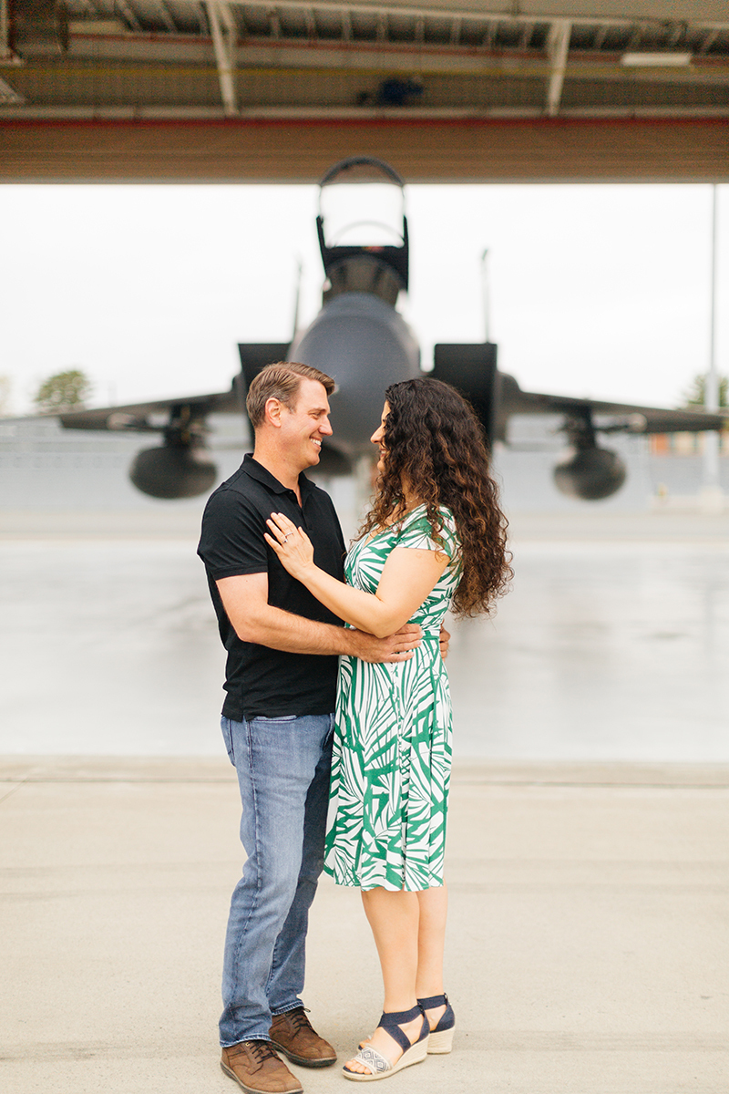 A pilot and his wife stand together in front an F-15 at Barnes Air National Guard Base wearing coordinated outfits for these F-15 fighter pilot family photos