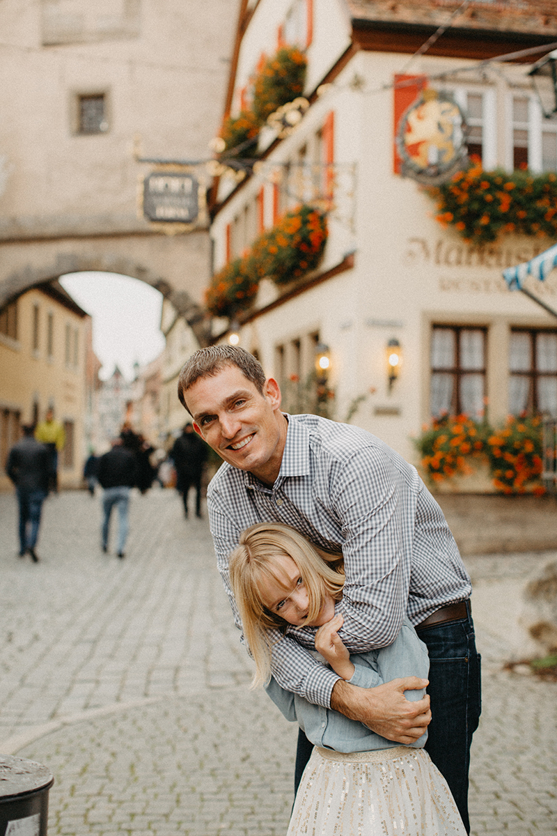 A father holds his daughter on his shoulders in Germany wearing coordinated outfits for a Rothenburg ob der Tauber family photography session
