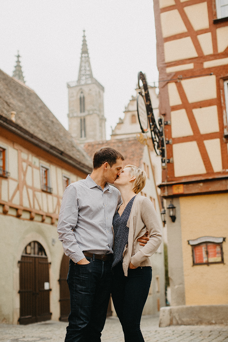 A couple hold one another and kiss in Germany wearing coordinated outfits for a Rothenburg ob der Tauber family photography session