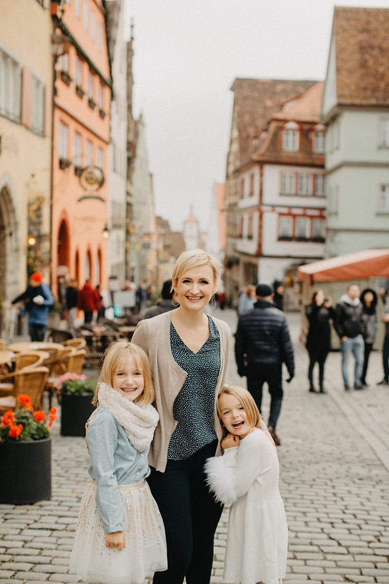 A mother walks with her daughters in Germany wearing coordinated outfits for a Rothenburg ob der Tauber family photography session