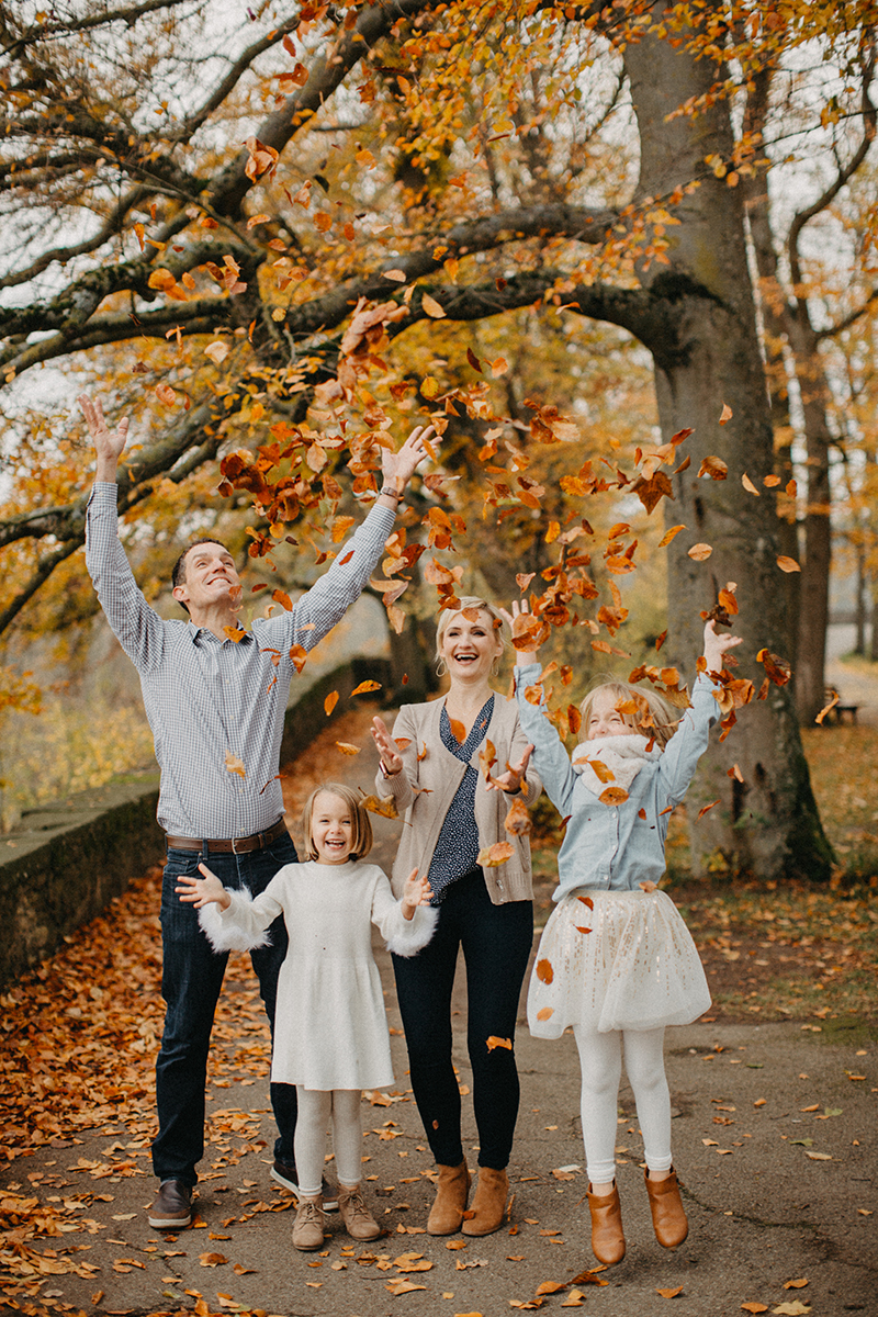 A family throws leaves together in Germany wearing coordinated outfits for a Rothenburg ob der Tauber family photography session