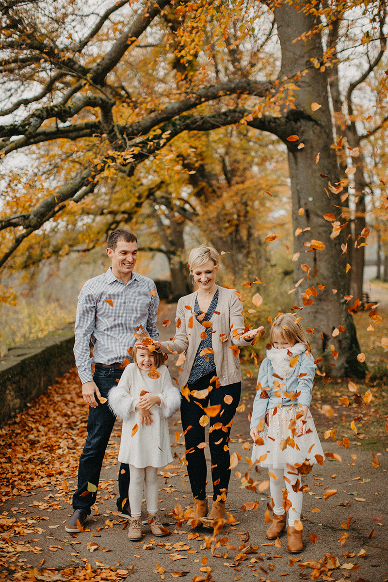 A family throws leaves together in Germany wearing coordinated outfits for a Rothenburg ob der Tauber family photography session