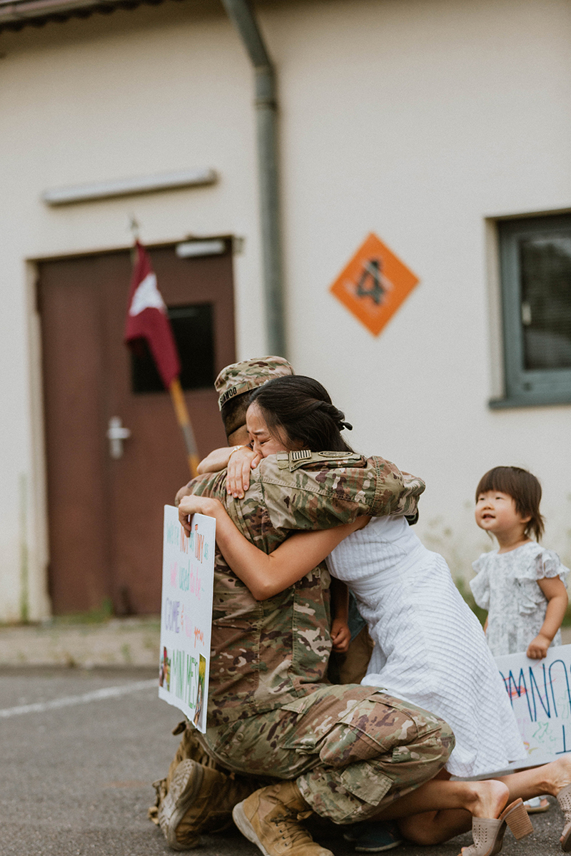 A woman hugs her husband as they reunite at the Rhineland Ordnance Barracks for Kaiserslautern homecoming photos in Germany
